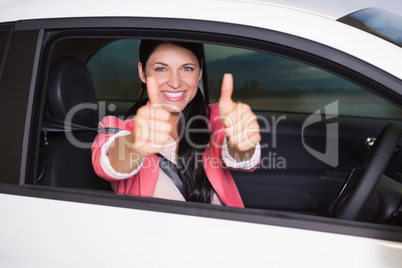 Smiling woman giving thumbs up in her car