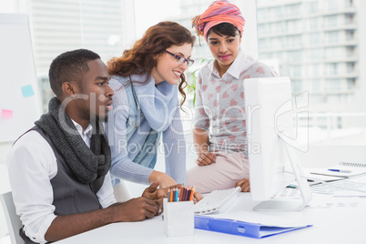 Cheerful coworkers working together with computer