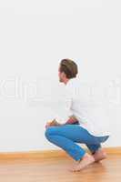 Casual man crouching on floor looking at wall