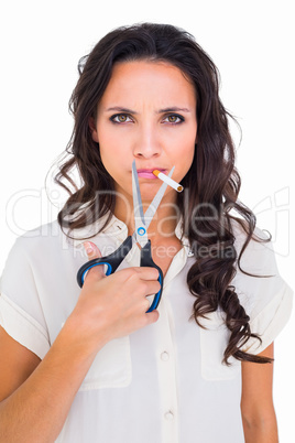 Pretty brunette cutting a cigarette