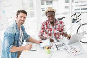 Smiling colleagues working with tablet and laptop