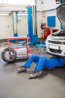 Mechanic lying and working under car