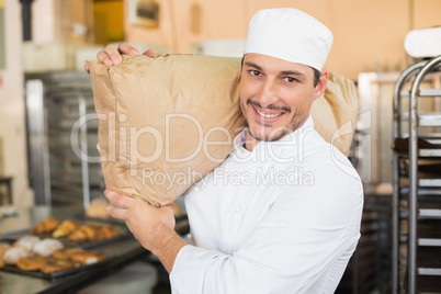 Smiling baker holding bag of flour