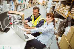 Warehouse worker and manager looking at laptop