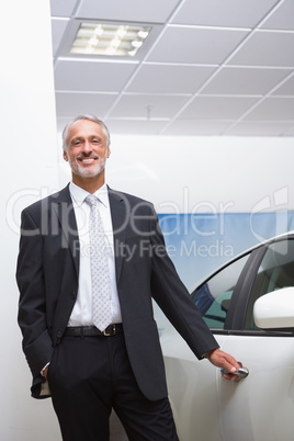 Smiling businessman holding a car door handles