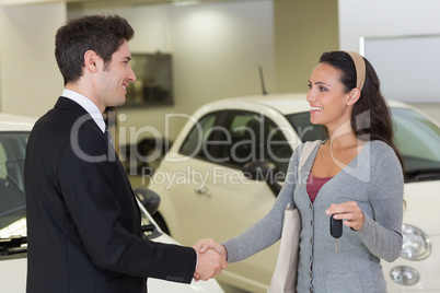 Businessman giving car key while shaking a customer hand