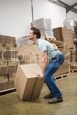 Worker with backache while lifting box in warehouse