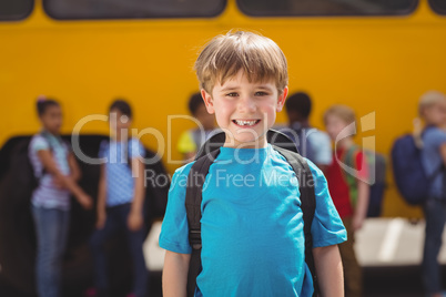 Cute pupils smiling at camera by the school bus