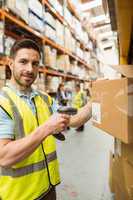 Warehouse worker scanning box while smiling at camera