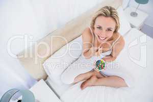 Smiling blonde eating sweets in bed