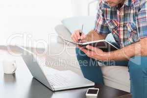 A man taking notes notebook sitting on a sofa