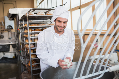 Smiling baker preparing dough in industrial mixer