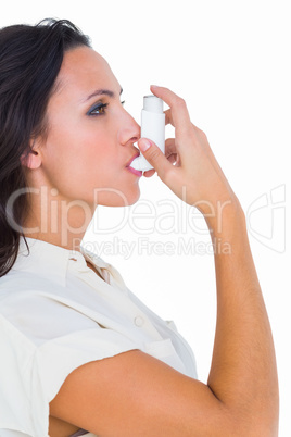 Asthmatic brunette using her inhaler