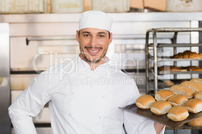 Happy baker showing tray of fresh bread