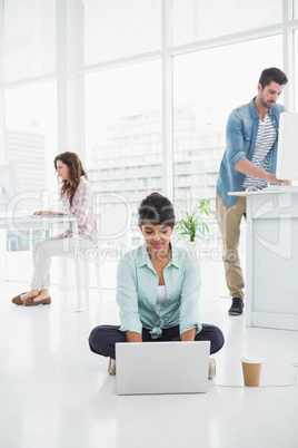 Casual businesswoman sitting on the floor using laptop