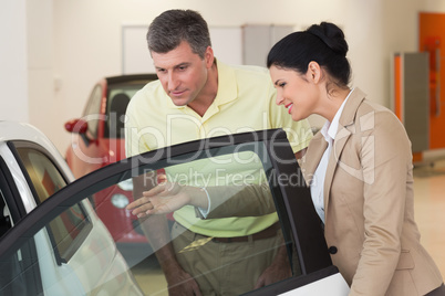 Businesswoman showing a car interior to her customers