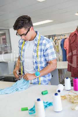 Fashion student cutting fabric with pair of scissors