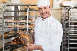 Smiling baker holding fresh loaf