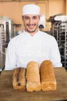 Smiling baker showing loaves of bread