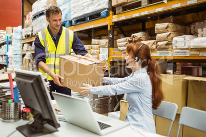 Warehouse worker and manager passing a box