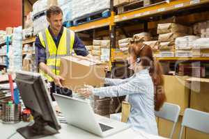 Warehouse worker and manager passing a box