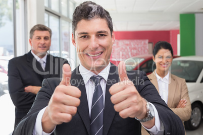 Smiling business team standing while one giving thumbs up