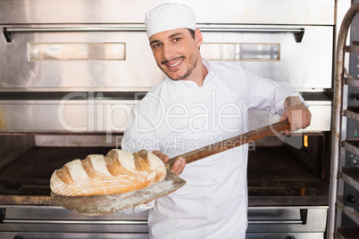 Happy baker taking out fresh loaf