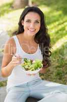 Pretty brunette eating bowl of salad