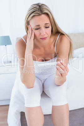 Anxious blonde woman looking her pregnancy test