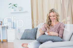 Happy blonde on couch eating salad