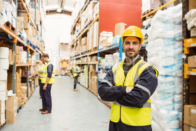 Smiling worker wearing yellow vest with arms crossed