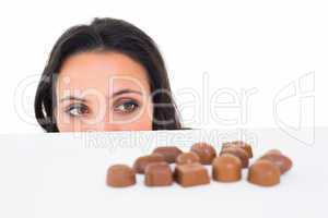 Pretty brunette peeking at chocolate