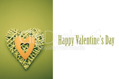 Composite image of wicker heart ornament with green paper cut ou