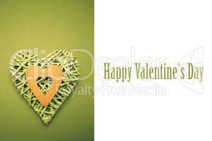 Composite image of wicker heart ornament with green paper cut ou