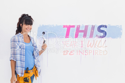 Composite image of woman painting wall blue and smiling