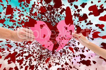 Composite image of hands holding two halves of broken heart