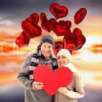 Composite image of happy mature couple in winter clothes holding