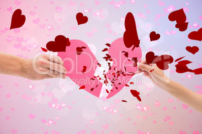 Composite image of hands holding two halves of broken heart