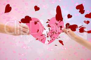 Composite image of hands holding two halves of broken heart