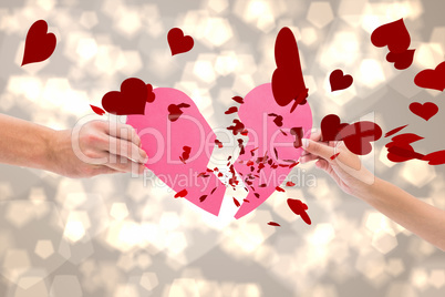 Composite image of hands holding two halves of broken heart