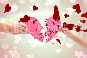 Composite image of hands holding two halves of broken heart