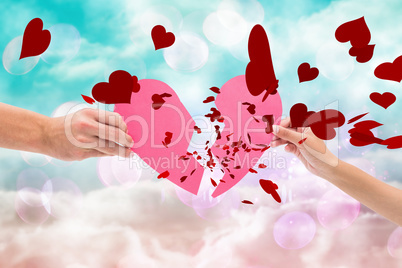 Composite image of hands holding two halves of broken heart