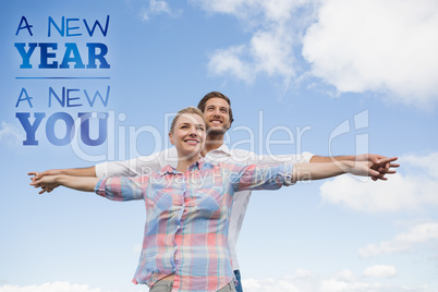 Composite image of happy couple standing outside with arms stret