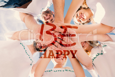 Composite image of happy volunteers with hands together against