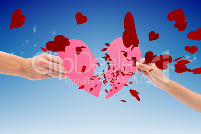 Composite image of hands holding two halves of broken heart