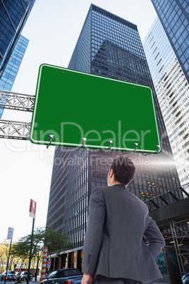 Composite image of businessman standing with hand on hip