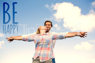 Composite image of happy couple standing outside with arms stret