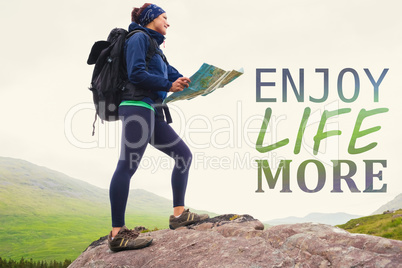 Composite image of woman standing on a rock holding map