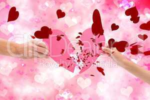 Composite image of hands holding two halves of broken heart