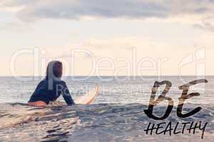 Composite image of rear view of a woman sitting on surfboard in